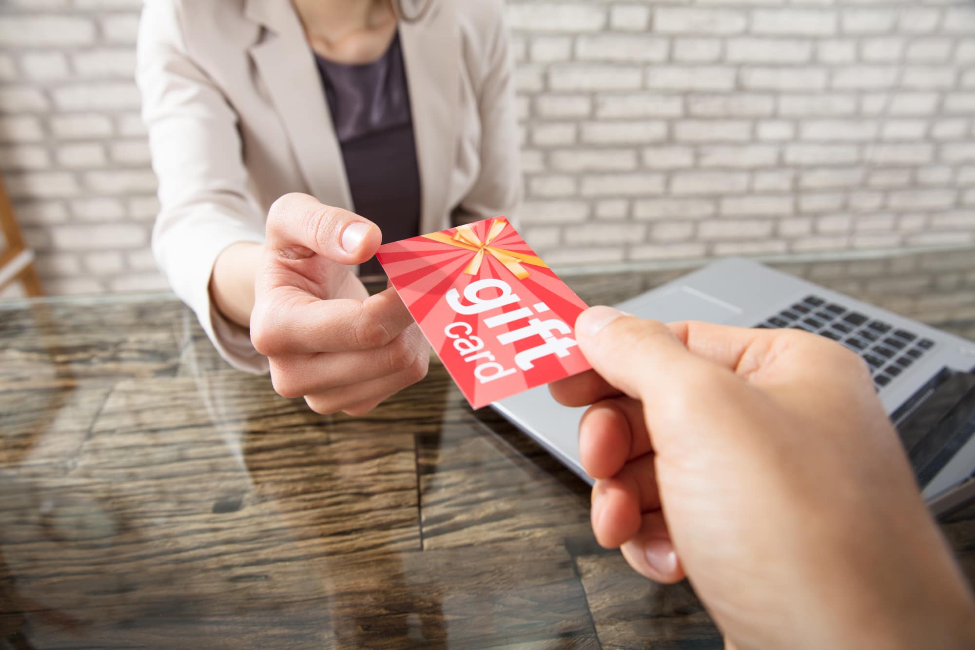 a hand giving a gift car to a cashier